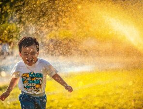 happy kid running through sprinkler