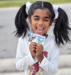 kid holding PETA Kids 2023 membership card and smiling