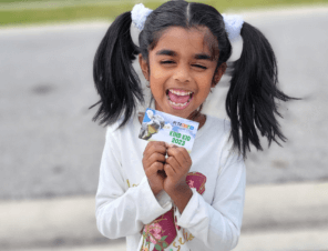 kid holding PETA Kids 2023 membership card and smiling