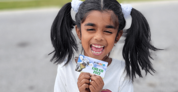 kid holding PETA Kids 2023 membership card and smiling