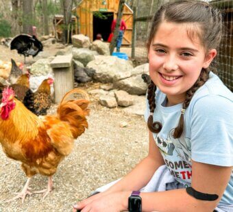Dani at an animal sanctuary smiling next to a chicken