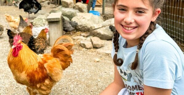 Dani at an animal sanctuary smiling next to a chicken
