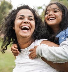 happy mom and her daughter playing outside on green grass