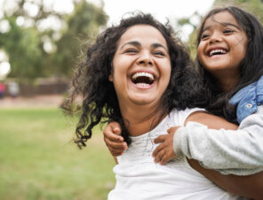 happy mom and her daughter playing outside on green grass