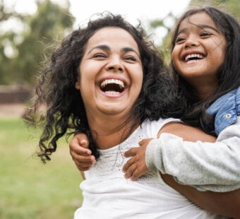 happy mom and her daughter playing outside on green grass