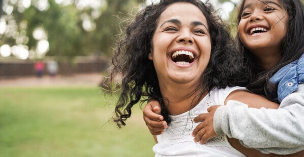 happy mom and her daughter playing outside on green grass