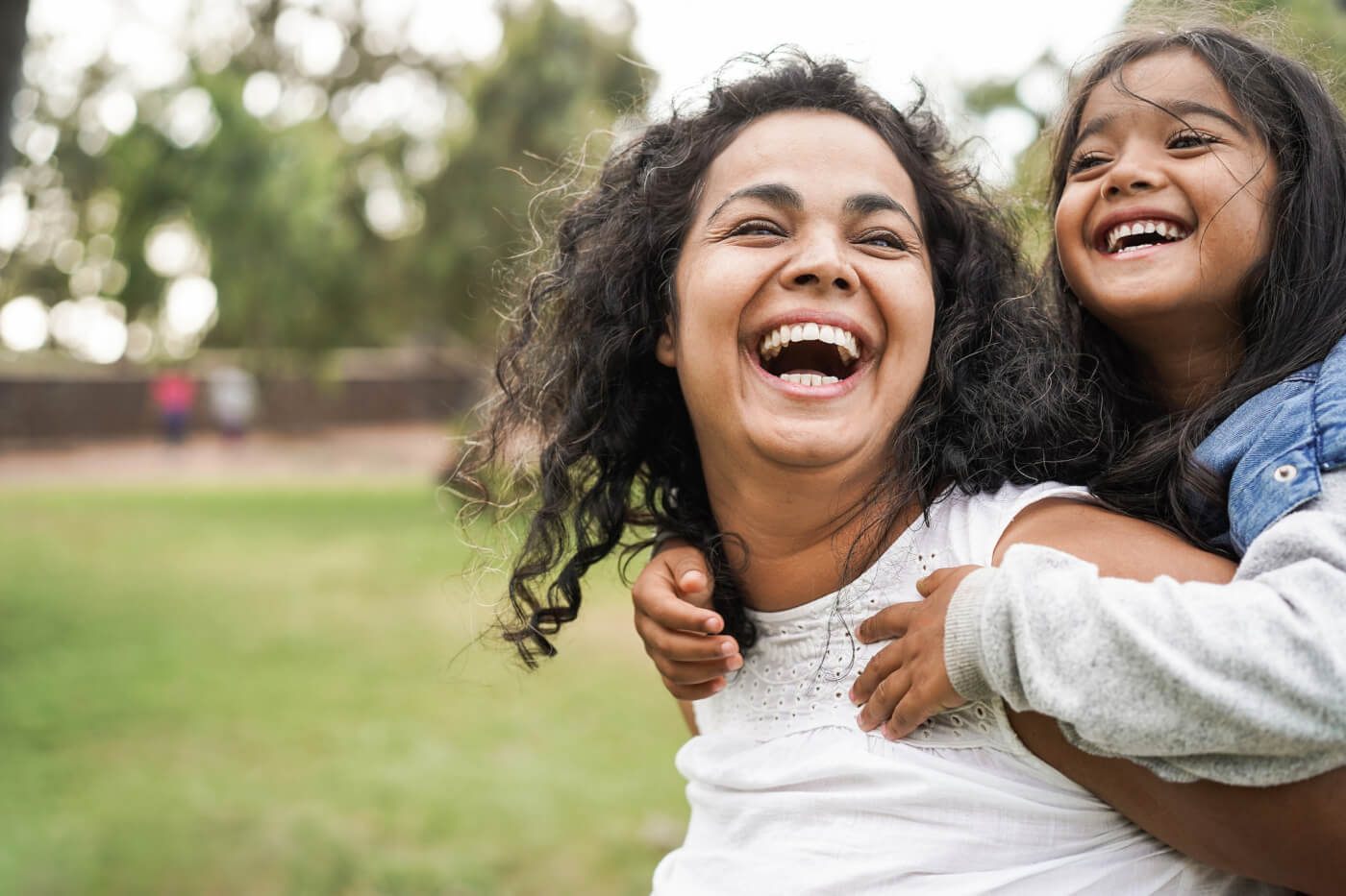 happy mom and her daughter playing outside on green grass