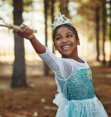 little girl dressed as a princess playing in the woods