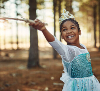 little girl dressed as a princess playing in the woods