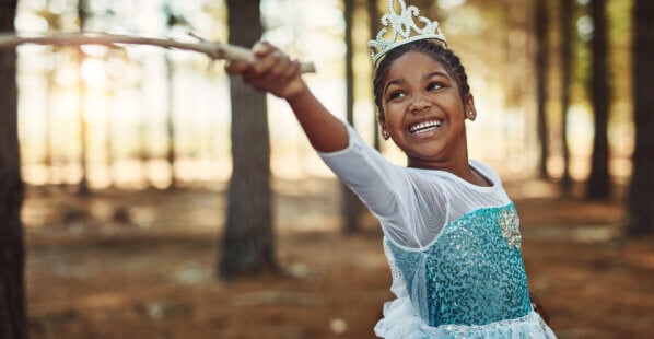 little girl dressed as a princess playing in the woods
