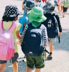 kids in a line at school with their school bags on and hats