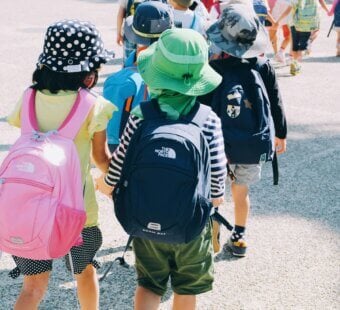 kids in a line at school with their school bags on and hats