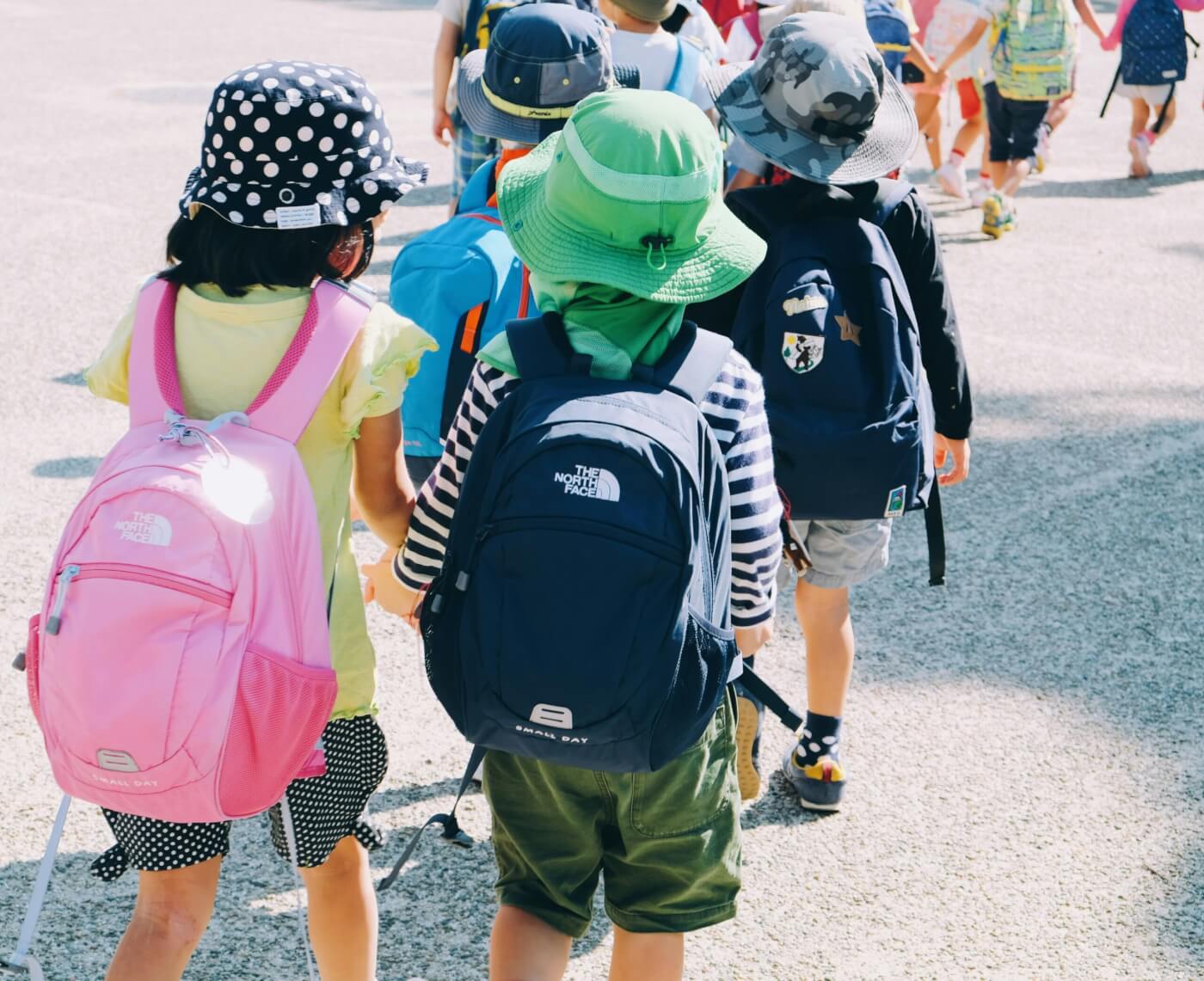 kids in a line at school with their school bags on and hats