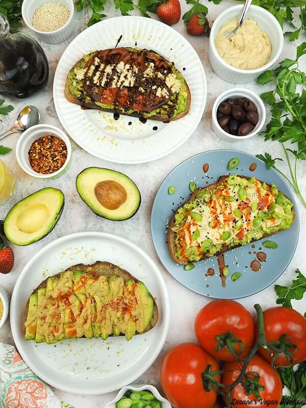 a table with three different types of avocado toast on it, with other decorations on the table--like tomatoes, sauces, and more.