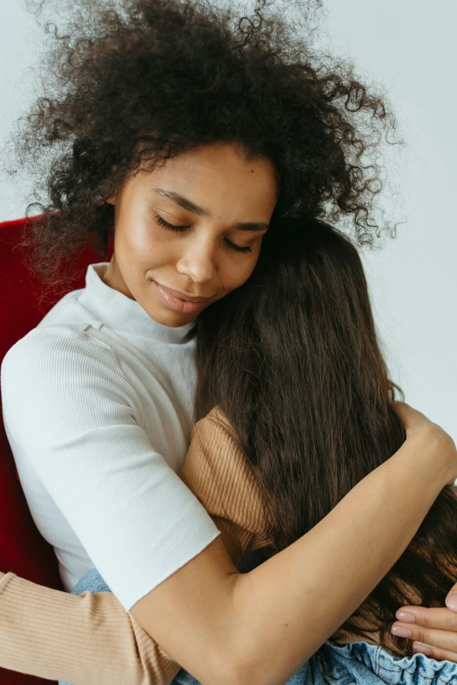 mom is holding her daughter in a tight hug.