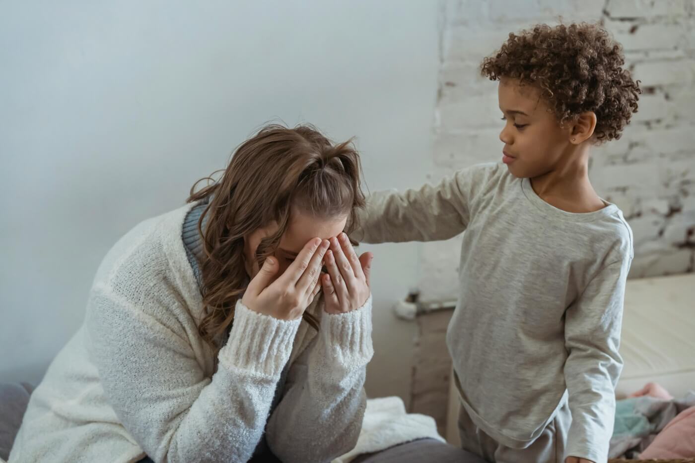 son is comforting his mom by touching her back while she cries.