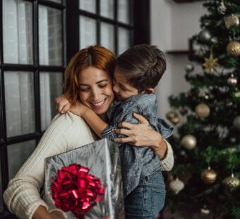 mother and son embracing each other while mom holds a gift.
